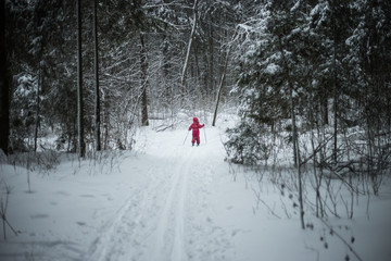 A young girl in red suit is learning skiing