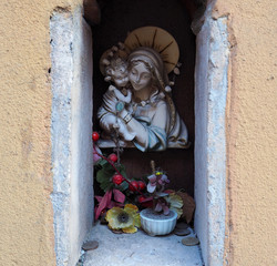 Popular religiosity in Italy. Little Madonna statue in a niche on the wall
