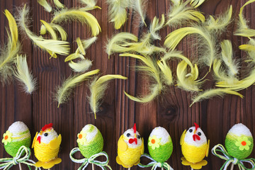 Easter eggs in nest and feather on brown wooden background