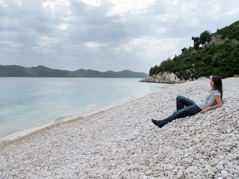 woman laying down in a pebbles paradisiac beach in Croatia