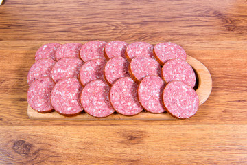 Close-up of chopped smoked sausage on a wooden board.