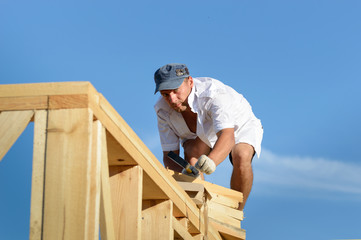 The young man, a builder builds a wooden frame house