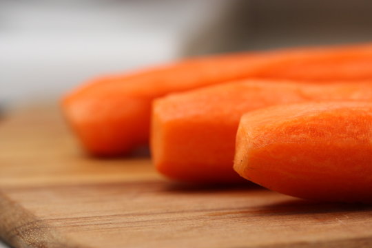 Peeled carrots on wooden chopping board.