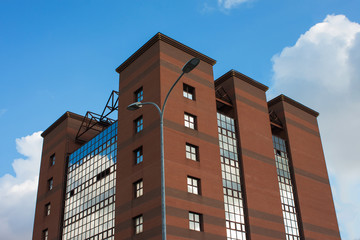 moderno edificio di mattoni e vetro su uno sfondo di cielo blu con nuvole. lampione coincide con il...
