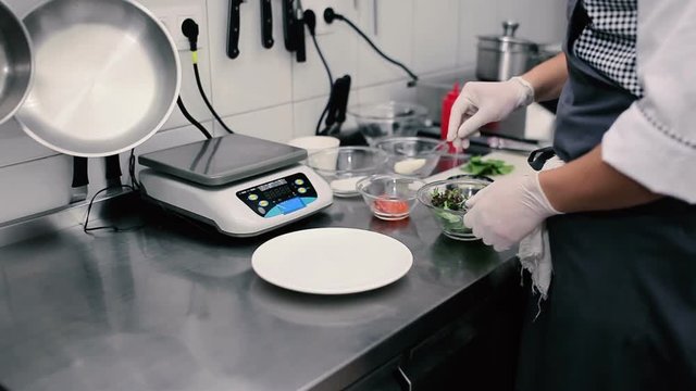 The cook mixes a salad on a kitchen in the restaurant