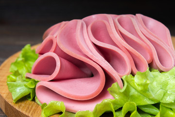 Sliced sausages with salad leaves on the wood background © detry26