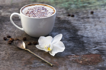 A cup of hot coffee and orchid flower on the wooden background. Traditional drink cappuccino or cocoa Wooden background Orchid flower