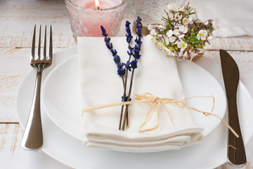 Romantic table setting, wedding, lavender, white small flowers, plates, napkin, candle, wood table, outdoors, kinfolk
