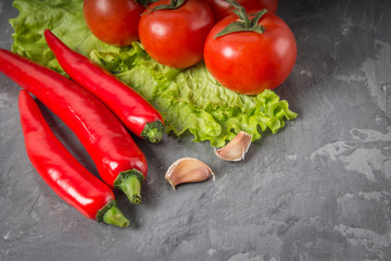 chili peppers, tomatoes, lettuce, garlic on a gray background.