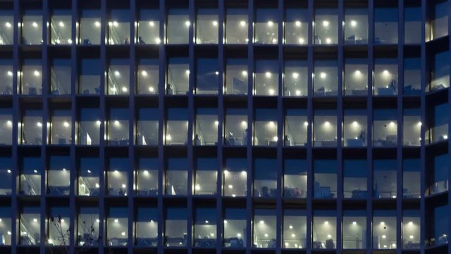 Office building, with illuminated interior at dusk, in the city of Barcelona.Motion Camera Panning Right and zoom out