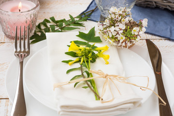 Wedding table setting, elegant, white yellow flowers, green leaves, candle, plates, blue napkin, wood table, outdoors, kinfolk, romantic