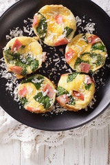 Omelet with spinach, ham and cheese on a plate close-up on the table. vertical top view