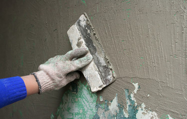 hand with a trowel plaster wall