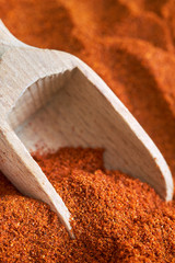 Closeup of red paprika powder with wooden scoop