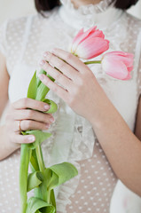 A girl in a white dress holding a pink tulips