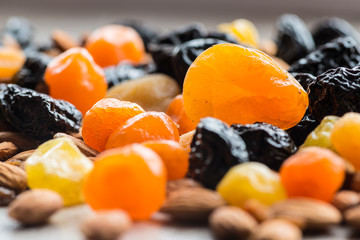 prunes, dried apricots, dried mandarins and almonds on a light wooden background
