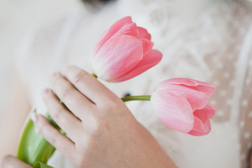 Obraz na płótnie Canvas A girl in a white dress holding a pink tulips