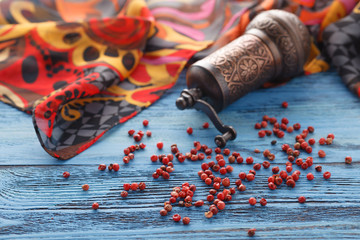 Red pepper on blue wooden table with silk scarf - obrazy, fototapety, plakaty