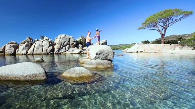 Father with his little son pointing out to famous pine tree on Palombaggia beach, Corsica, France 
