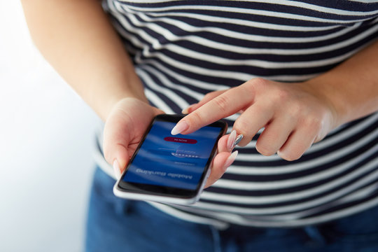 Female hands using mobile banking on black smartphone