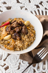 Pilaf - Rice with Meat and Vegetables on the table. Pilaf with lamb and garlic zira