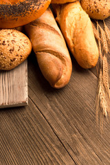 Bread, baguette, loaf and buns on the wooden desk. Vertical