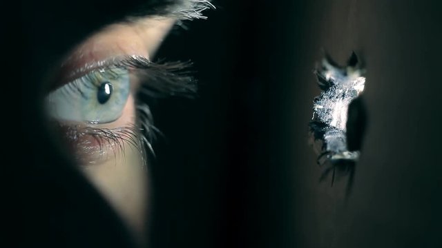 Peeping eye through hole, horror scene