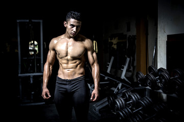 Fototapeta na wymiar Young man exercising in dark and old gym