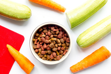 Dry dogfood with carrot and zucchini on table background top view