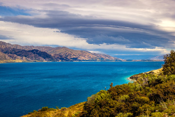 Landscape view of Lake Hawea and mountains with dramatic sky, NZ