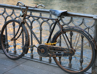 Fototapeta premium black old bike leaning on the bridge above the river