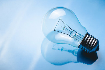 Light bulb on glossy reflective glass surface.