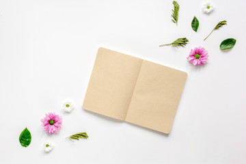 Petals and copybook on white table background top view mock up
