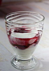 yoghurt with fruit and gel , raisins and nuts in a glass cups on white board