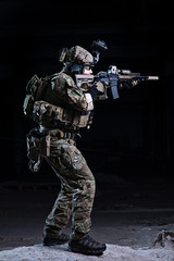 Soldier aiming from rifle on dark background/Soldier with rifle in helmet with night vision device aiming to target on dark background