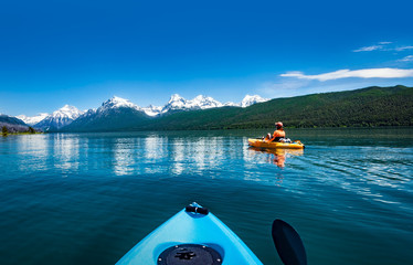  Kayaking in the spring by snow covered mountains on Lake McDonald in Glacier National Park Montana