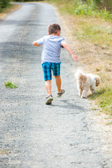 Young child running down the road with small dog