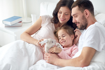 Obraz premium happy child with toy and parents in bed at home