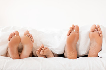 bare soles of happy family feet in bed at home