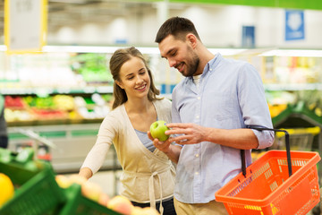 happy couple buying apples at grocery store