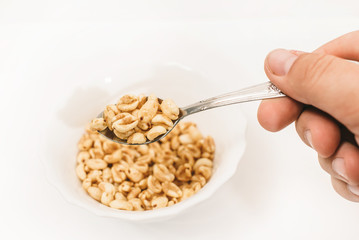 dry Breakfast in white plate on a white background (the human hand holds a spoon)