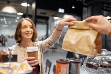 woman taking paper bag from seller at cafe