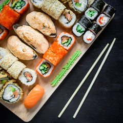 Japanese food - sushi rolls and sauce on a black wood background. Top view. Flay lay