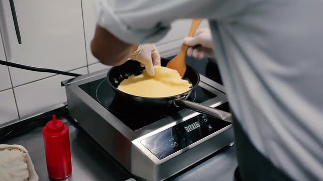 Cook adds an omelet in a pan.