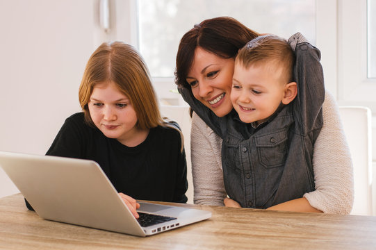 Mom and kids earching for family pictures on computer at home.