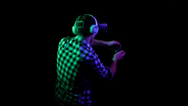 Man plays on gamepad in virtual reality glasses. Back view