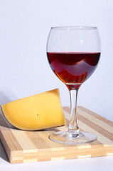 Glass of red red wine grapes and chees on wooden table.