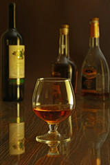 Glass of cognac, brandy or whiscy on mirror table. bottles in a bar on the background