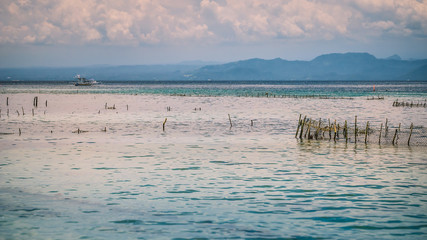 Seaweed plantation farm by Hight Tide in Nusa Penida, Bali in Clouds on Background, Indonesia