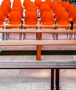 Red and orange Empty plastic chairs and Iron benches kept for people before a gathering